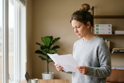 Femme examinant des feuilles de papier de bureau dans un home office moderne et rangé